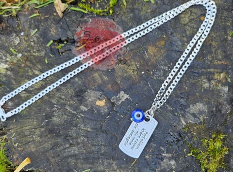 White lanyard with blue eye clasp and white ID badge on moss-covered stone surface